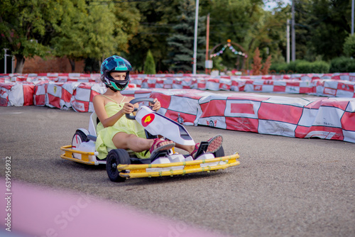 A young go-kart racer on the racetrack. The concept of speed and sports for children in the summer