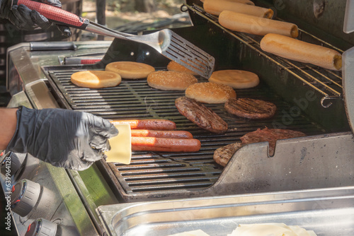 Φωτογραφία Process of cooking meat for burgers and cheeseburgers, sausages for hot dogs, buns on a grill with burning coals