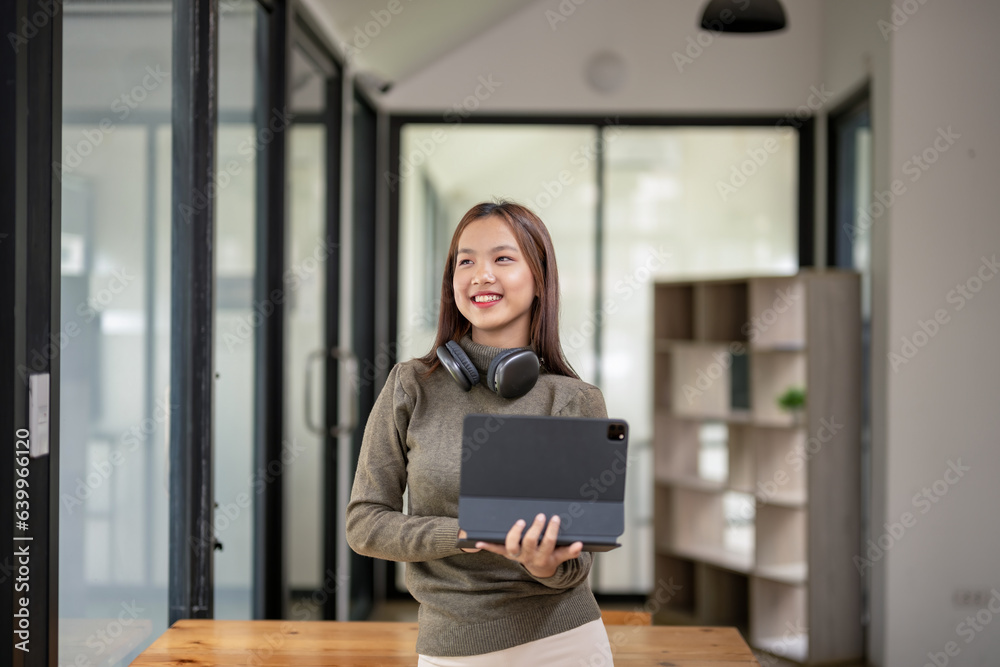 Female college student holding a tablet in her workspace Female college student holding a tablet in her workspace