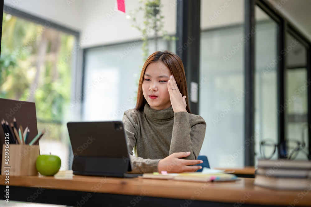 Female college student sitting bored studying online on a laptop. Tired and headache.