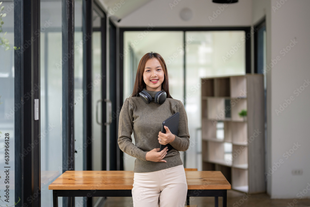 Female college student holding a tablet in her workspace Female college student holding a tablet in her workspace
