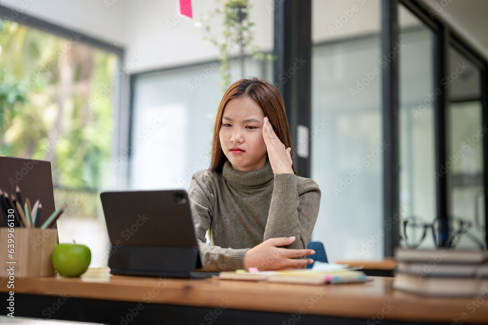 Female college student sitting bored studying online on a laptop. Tired and headache. Female college student sitting bored studying online on a laptop. Tired and headache.