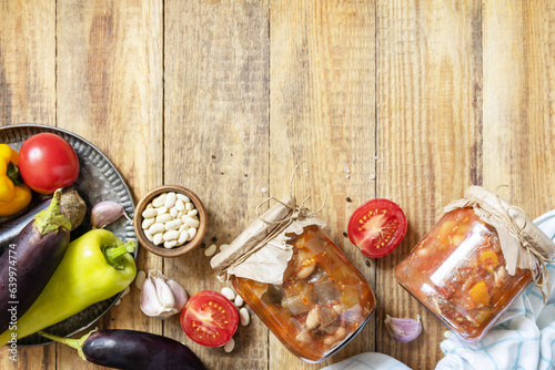 Healthy homemade fermented food. Salad eggplant with beanson a rustic table. Home economics, autumn harvest preservation. View from above. Copy space. photo