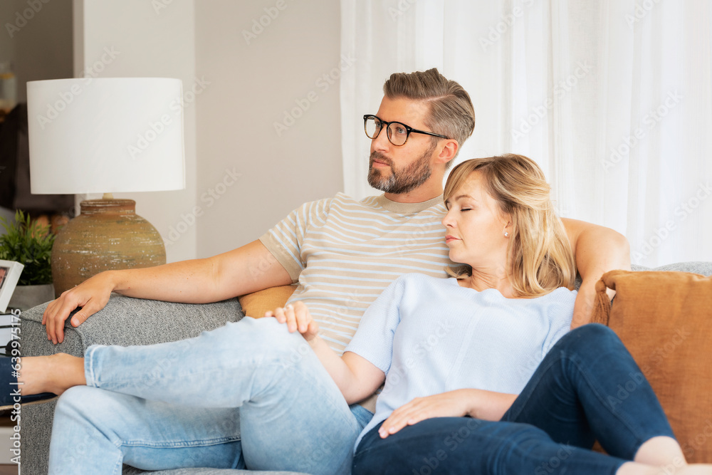 Mid aged couple relaxing on the sofa at home together