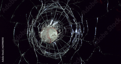 Ball of Baseball breaking Pane of Glass against Black Background