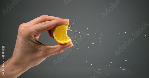 Hand of Woman Squeezing Orange against Black Background
