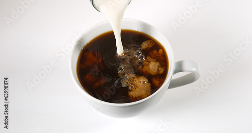 Milk poured into a Cup of Coffee against White Background