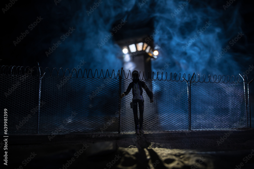 Obraz premium Old prison watchtower protected by wire of prison fence at night. Creative art decoration. Selective focus