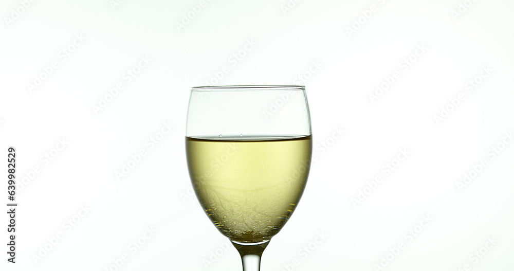 White Wine being poured into Glass, against White Background
