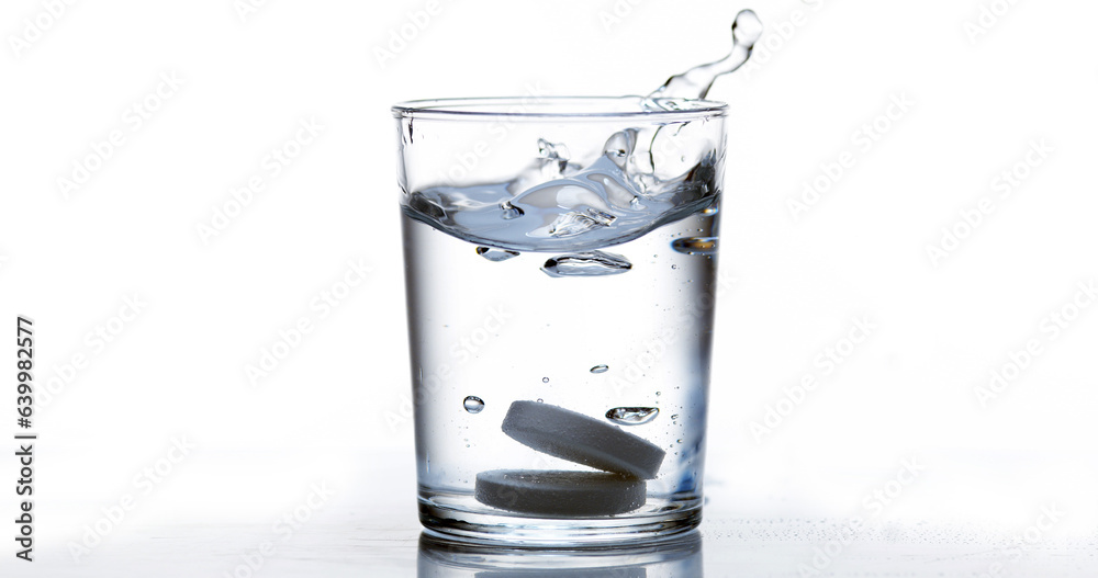 Tablets Falling and Dissolving into a Glass of Water against White Background Tablets Falling and Dissolving into a Glass of Water against White Background