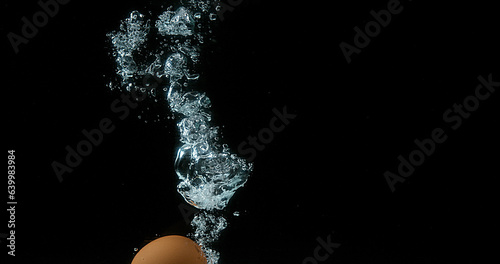 Chicken's Eggs entering Water against Black Background