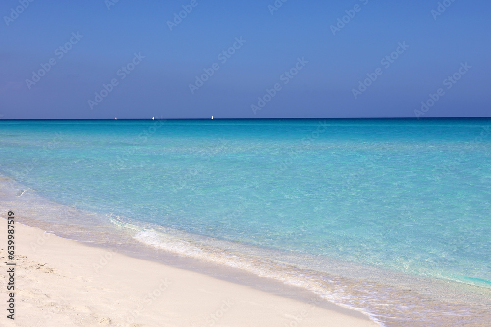 Empty sea beach with white sand, view to azure waves and blue sky with clouds. Caribbean coast, Background for holidays on a paradise nature Empty sea beach with white sand, view to azure waves and blue sky with clouds. Caribbean coast, Background for holidays on a paradise nature