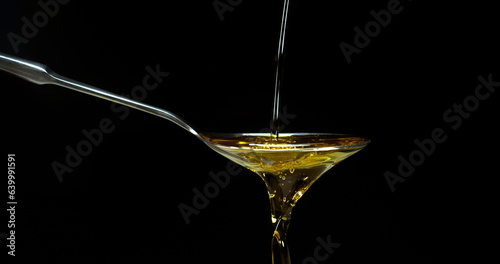Olive Oil, Falling in a Spoon against Black Background