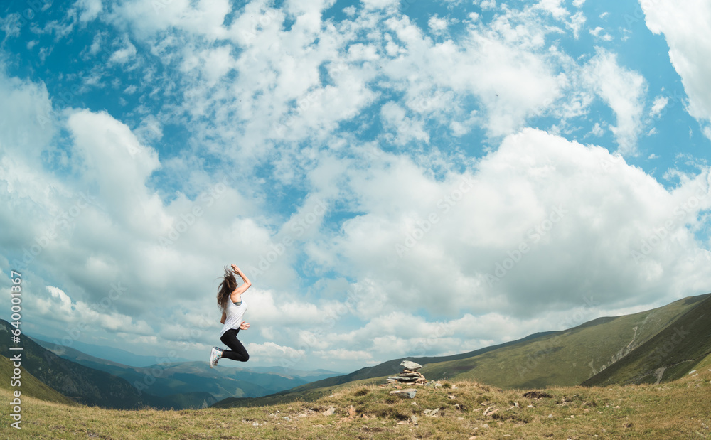 A girl enjoys the walk in the mountain landscape. The girl jumps up.