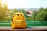 Backpack with various colorful stationery on the table on blurred nature town background