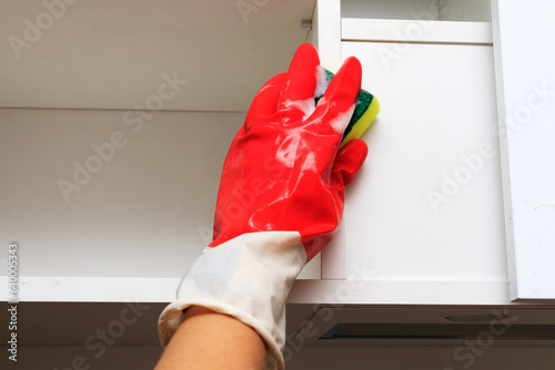 Cleaning in the kitchen. Cleaning of dirt from kitchen cabinets with a white facade