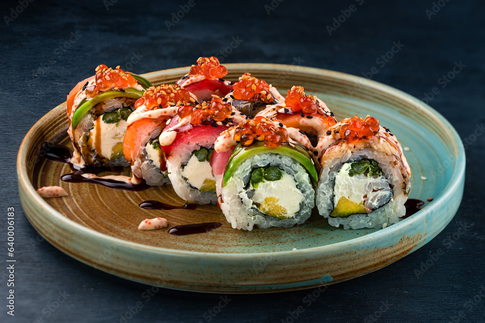 Sushi rolls with tuna, salmon, eel, cream cheese, avocado, red caviar and sauce in plate. Sushi rolls with tuna, salmon, eel, cream cheese, avocado, red caviar and sauce in plate.