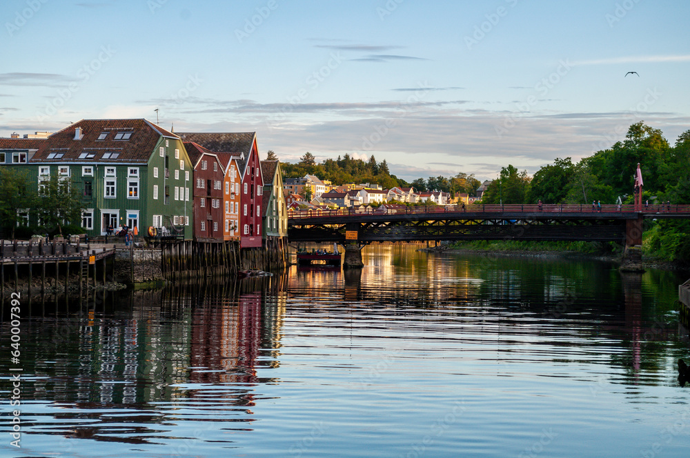 Fjord with wooden bridge and embankment with colorful wooden houses in Trondheim, Norway.