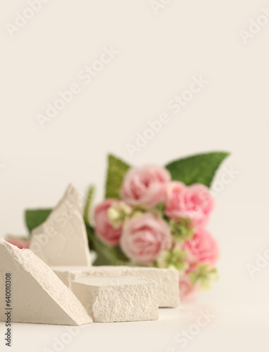 Empty stack of stones platform podium and rose flower bouquet on beige background. Minimal empty display product presentation scene. photo