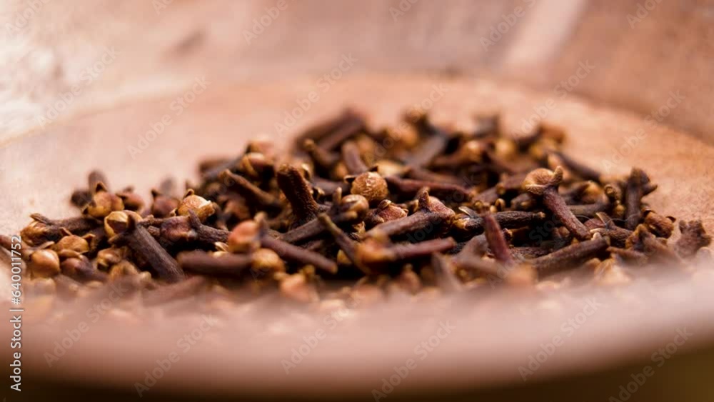 Aromatic dry cloves falling in slow motion into a wooden bowl. Spices and seasonings. Rotation