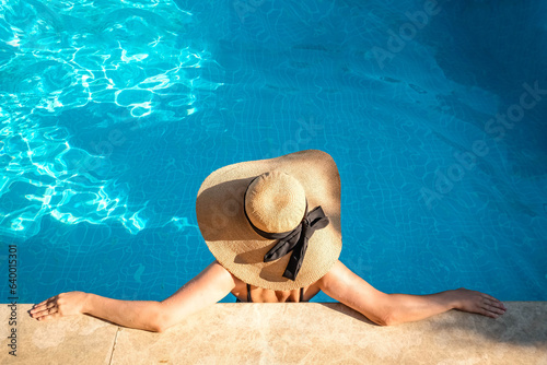 Beautiful girl in swimsuit relaxing by the pool during her summer holiday. Copy space. Summer and vacation, sunbathing wellness Lifestyle concept.