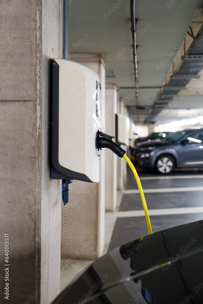 Recharging electric cars at the charging station in the underground parking. The concept of ecological energy systems. Electric cars in an underground car park at a charging station Recharging electric cars at the charging station in the underground parking. The concept of ecological energy systems. Electric cars in an underground car park at a charging station