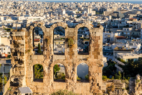 Arches of the Odeon of Herodes Atticus lit by sunset light with Athens's central quarters on the background. Greece. photo