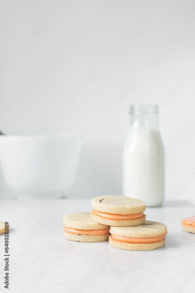 Vanilla sugar cookies with orange filling, round rosemary cookies filled with orange cream, no spread cookies on a marble tray with a white background Vanilla sugar cookies with orange filling, round rosemary cookies filled with orange cream, no spread cookies on a marble tray with a white background