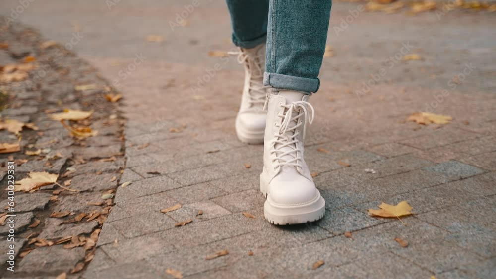 Smiling fashionable young woman in pink jacket and white boots walking outdoors in city park. Seasonal style, autumn season concept. Slow motion Smiling fashionable young woman in pink jacket and white boots walking outdoors in city park. Seasonal style, autumn season concept. Slow motion