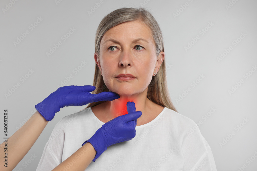 Endocrinologist examining thyroid gland of patient on light grey background, closeup Endocrinologist examining thyroid gland of patient on light grey background, closeup