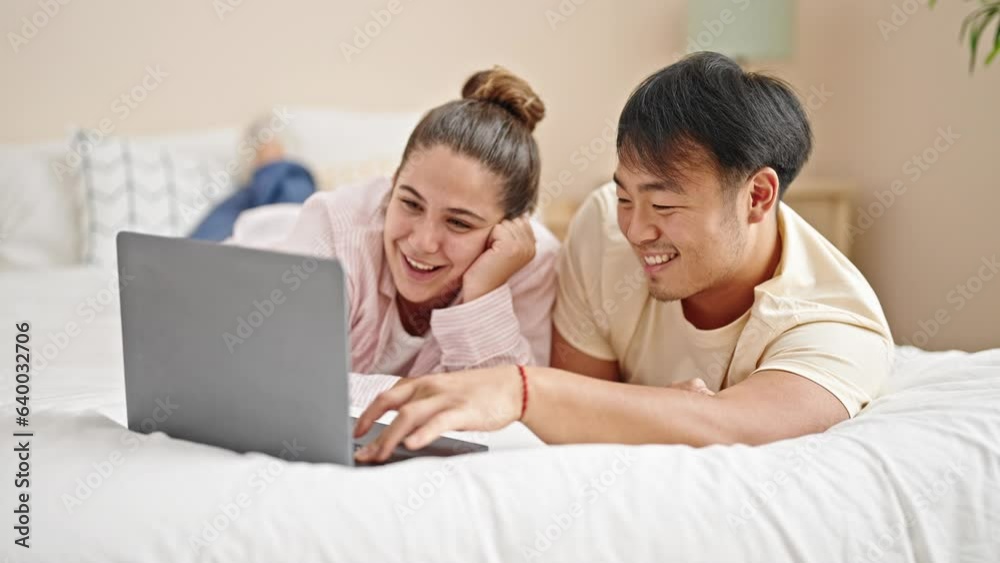 Man and woman couple lying on bed using laptop at bedroom Man and woman couple lying on bed using laptop at bedroom