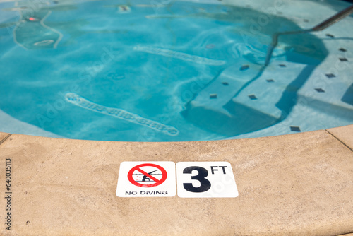 Edge of swimming pool with No Diving warning sign and 3 ft depth marker photo