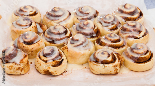 Soft and fluffy cinnamon swirls topped with sugar glaze on wooden background..