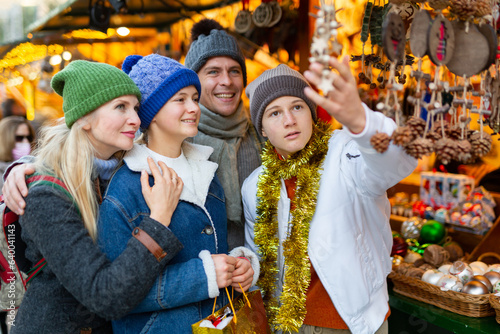 Winter holidays and celebration concept - happy mother, father and teenagers at christmas market