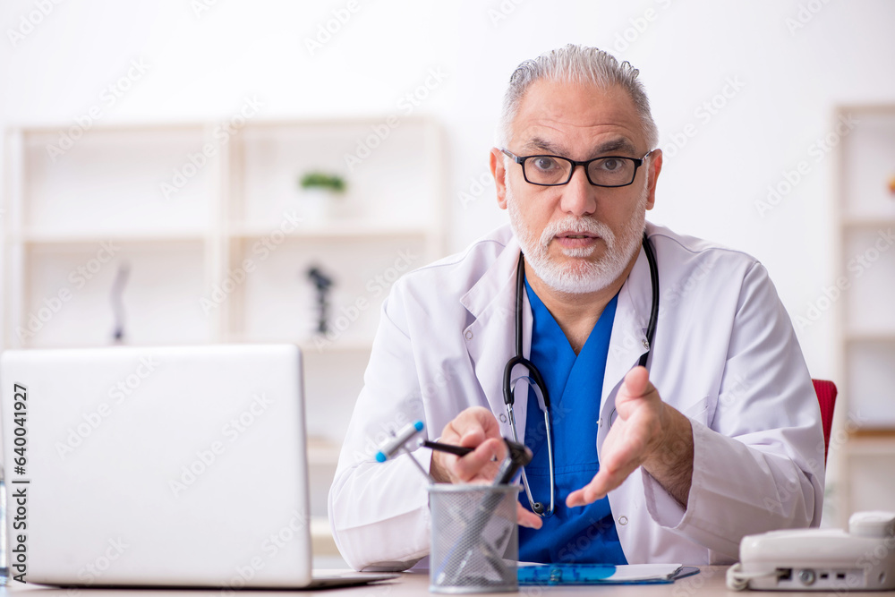 Old male doctor working in the clinic Old male doctor working in the clinic
