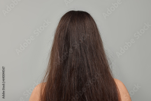 Woman with damaged hair before treatment on light grey background, back view