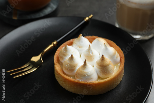 Tartlet with meringue served on black table, closeup. Delicious dessert