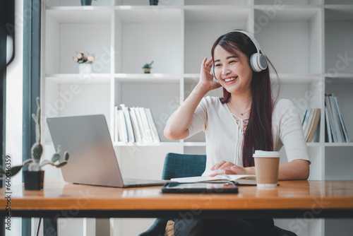 Pretty young woman listening to music with laptop computer and relaxing while sitting on chair at home.