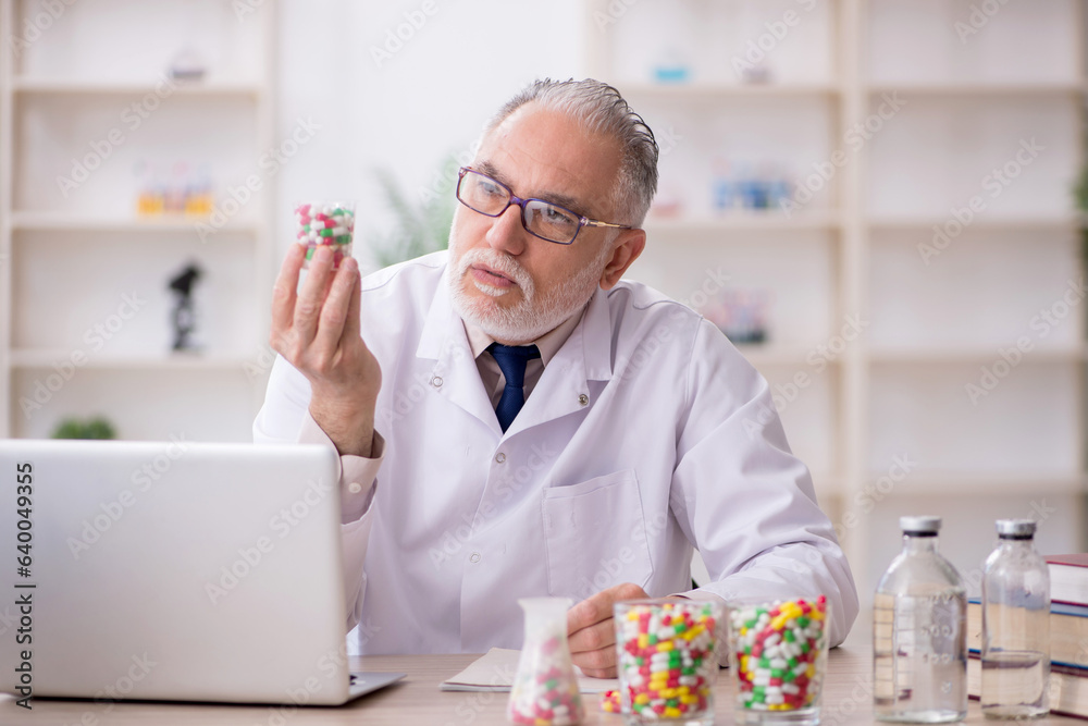 Old male doctor suggesting pills in the clinic