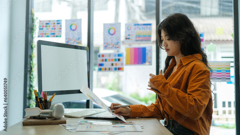 Side view of young creative woman using graphic tablet, working with color swatch samples on computer screen at workstation. Side view of young creative woman using graphic tablet, working with color swatch samples on computer screen at workstation.