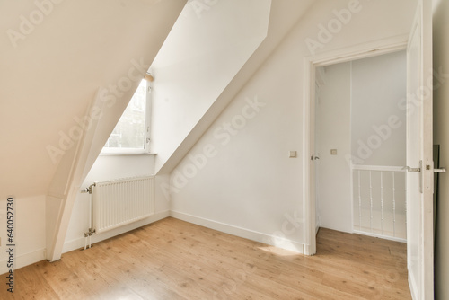 a room with wood flooring and an attic style window in the room has white walls  wooden floors and a rad door