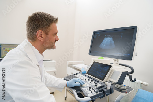 Professional sonographer looking at the screen during procedure of ultrasound. High quality photo
