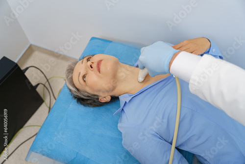 Adult woman having thyroid exam with ultrasound at doctor's office. Healthcare concept