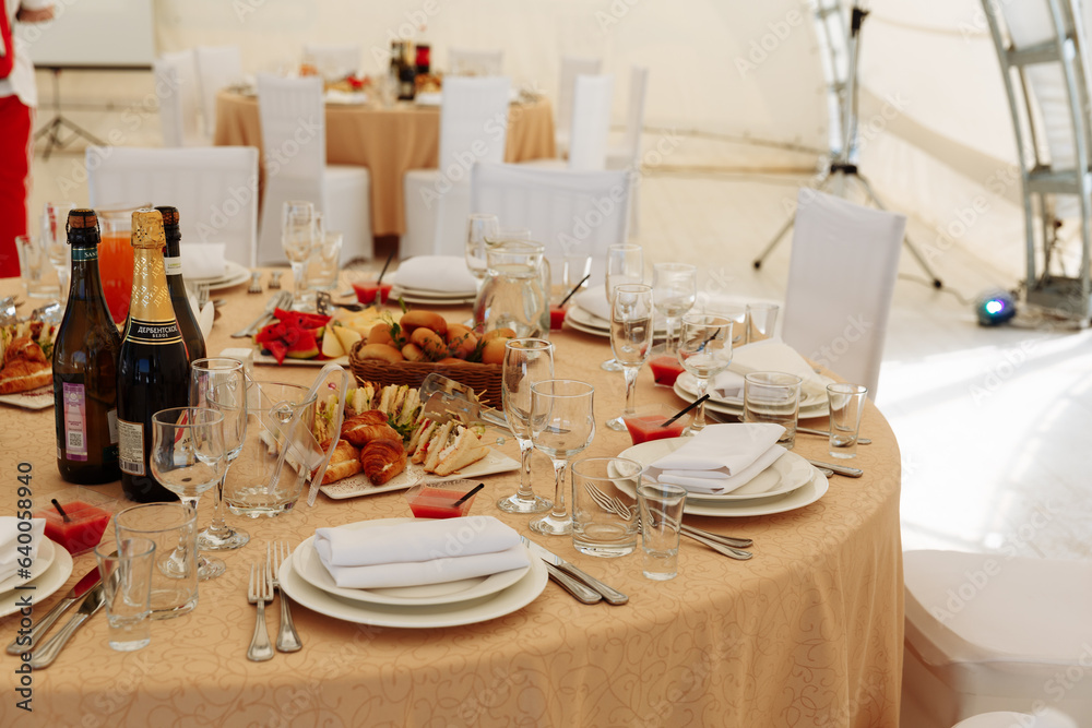 The catering table set service with silverware and glass stemware at a restaurant before the party. Selective focus on the champagne glasses