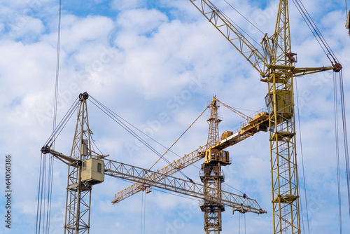 A crane and a building under construction against a blue sky background. Builders work on large construction sites, and there are many cranes working in the field of new construction. © Анатолий Савицкий