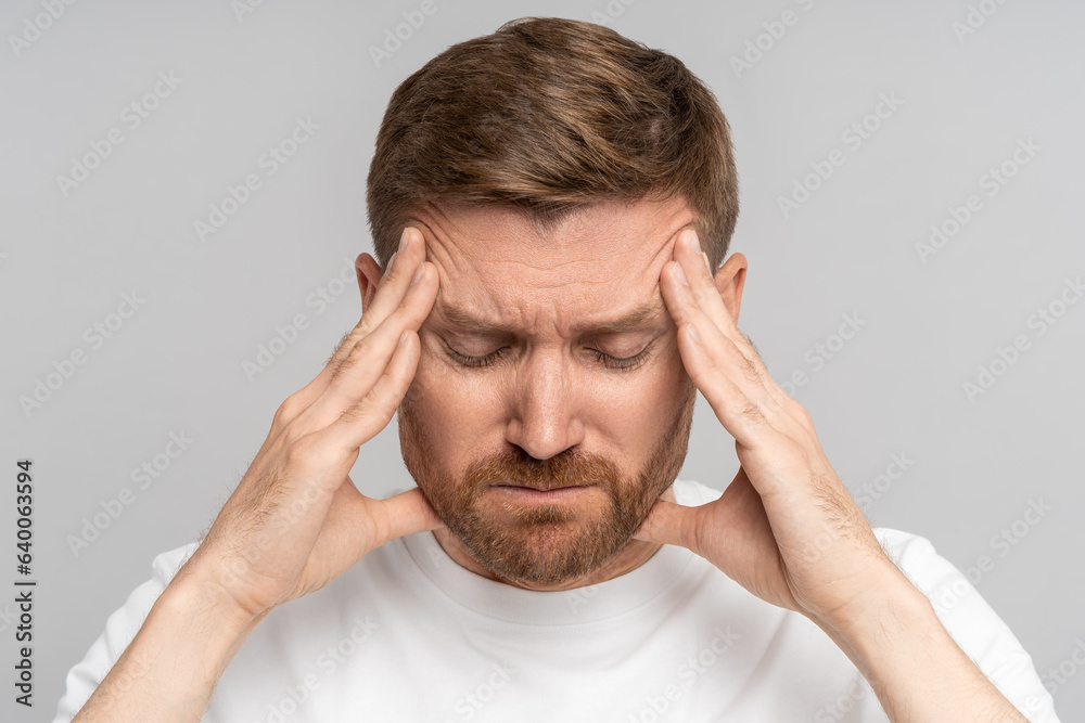 Irritated exhausted man with eyes closed presses fingers to temples from headache, failure, fatigue, difficult choose, isolated background. Overwhelmed male with professional burnout tries concentrate Irritated exhausted man with eyes closed presses fingers to temples from headache, failure, fatigue, difficult choose, isolated background. Overwhelmed male with professional burnout tries concentrate