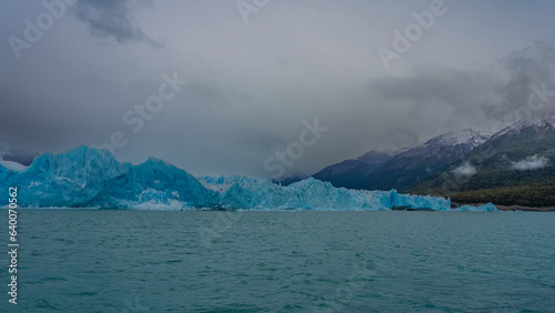 Beautiful glacier Perito Moreno. A wall of blue ice rises above a turquoise lake. Ripples on the water. The surrounding mountains are hidden in clouds and fog. El Calafate. Los Glaciares National Park