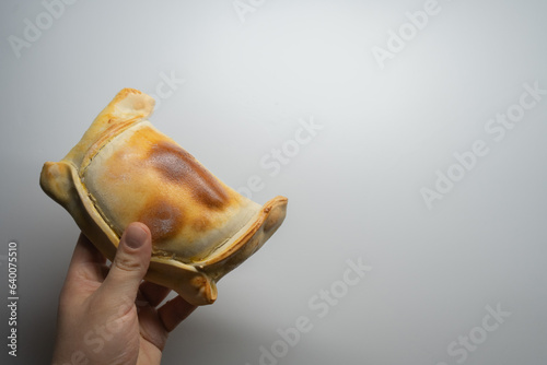 man's hand holding a chilean empanada de pino on white background photo