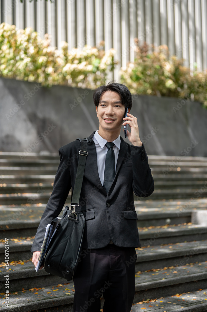 A businessman is talking on the phone while walking down the stairs in front of the building. A businessman is talking on the phone while walking down the stairs in front of the building.