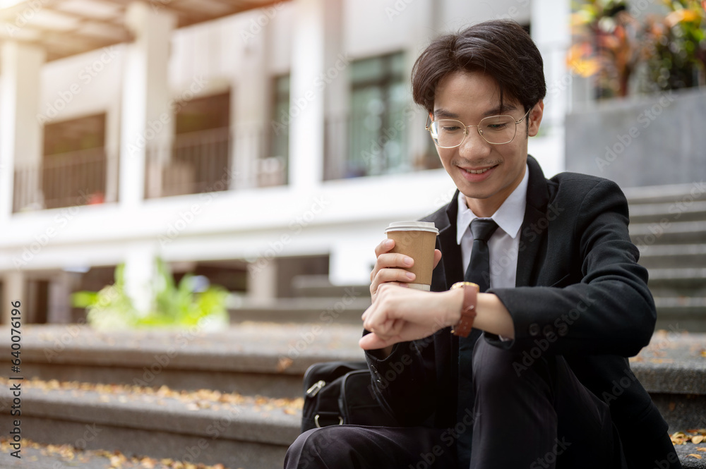 A businessman checking time on his watch while sitting on a staircase in front of the building. A businessman checking time on his watch while sitting on a staircase in front of the building.